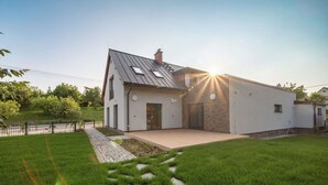 A modern house with a sloped roof, a paved driveway, and a well-maintained lawn.