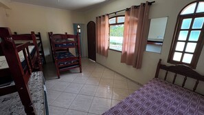 Ein Zimmer mit Etagenbetten, einem Vorhangfenster, einem Spiegel und einem Fliesenboden.
