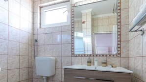Een badkamer met toilet, wastafel, spiegel en douche.