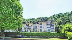 Un edificio a più piani con balconi, immerso nel verde sotto un cielo sereno.
