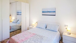 Una camera da letto con un letto, comodini, uno specchio, un quadro e un armadio.