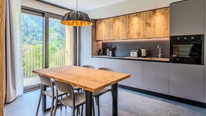 Une cuisine moderne avec un revêtement mural en bois, un four encastré et un coin repas comprenant une table et des chaises en bois.