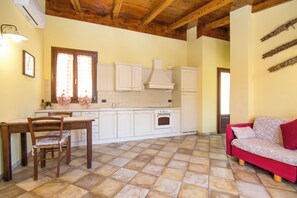 Una cocina con armarios blancos, una mesa de comedor de madera y un sofá rojo.