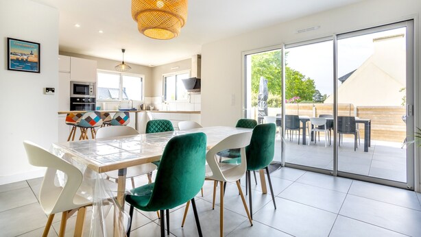 A modern dining area with a glass table, green chairs, and a wicker pendant light. - Holiday Home “Maison Concarneau” with Private Terrace, Garden & Wi-Fi (Concarneau)