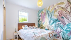 A bedroom with a bed, a nightstand, a window, and a wall mural. - Holiday Home “Maison Concarneau” with Private Terrace, Garden & Wi-Fi (Concarneau)