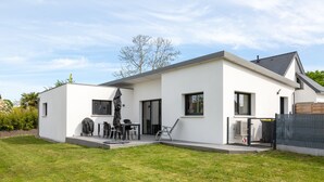 A modern house with a patio, a grill, and a fenced yard. - Holiday Home “Maison Concarneau” with Private Terrace, Garden & Wi-Fi (Concarneau)