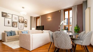 A modern living room with a sofa, dining table, chairs, and a flat-screen TV. - "View Brera Penthouse" Private Jacuzzi + Duomo 5 Min (Milano)