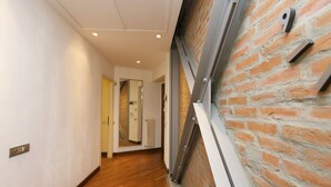 A hallway with a wooden floor, a brick wall, and a metal-framed window. - "View Brera Penthouse" Private Jacuzzi + Duomo 5 Min (Milano)