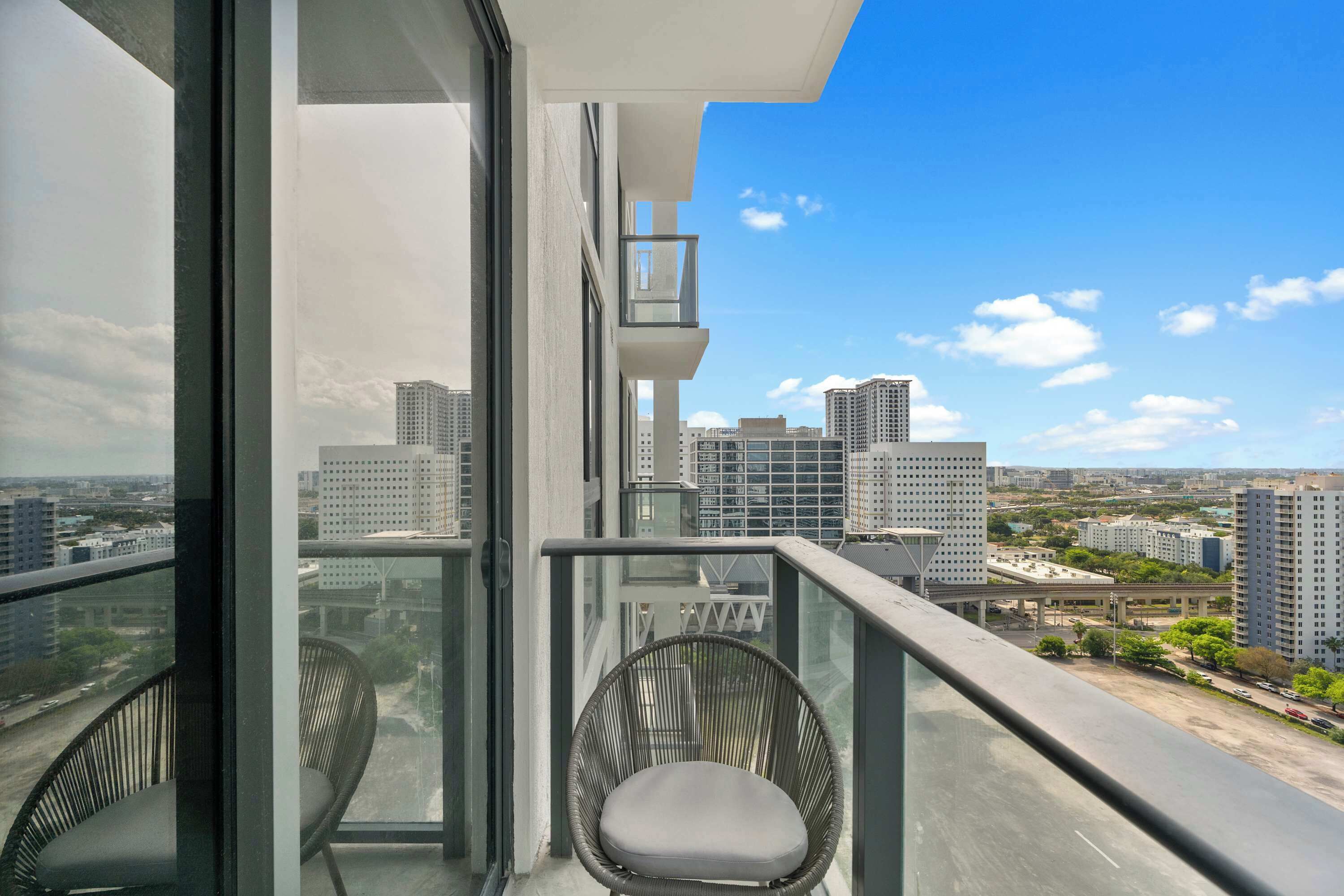 Uma varanda com vista para um horizonte urbano, incluindo edifícios altos e um céu claro.