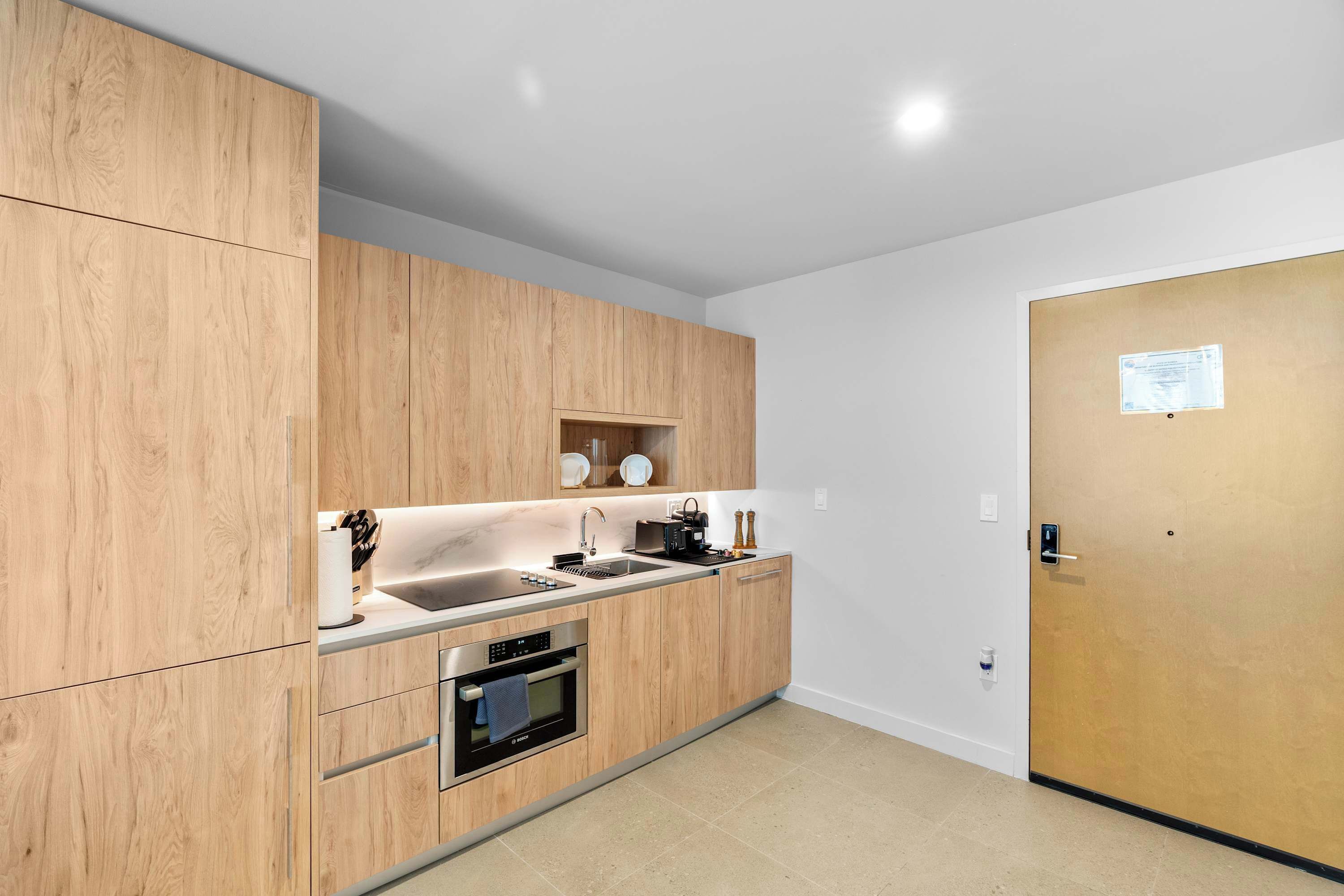 Une cuisine moderne avec des meubles en bois, des appareils électroménagers en acier inoxydable et un four encastré.