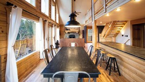 A wooden interior with a long dining table, chairs, a bar area, and a fireplace. - Lakeview Mountain Cabin with Wraparound Deck, Hot Tub & Wood Burning Fireplace. (Twin Lakes)