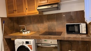 A kitchen with wooden cabinets, a microwave, a washing machine, and a stove.