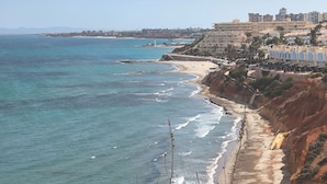 A coastal view with a beach, ocean, and buildings in the background. - Playa Flamenca With Terrace (Orihuela)