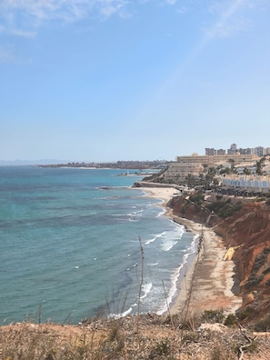 A coastal view with a beach, ocean, and buildings in the background. - Playa Flamenca With Terrace (Orihuela)