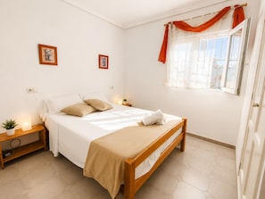 A bedroom with a bed, bedside tables, a window with curtains, and two wall-mounted pictures. - Playa Flamenca With Terrace (Orihuela)