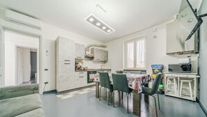 A modern kitchen with a dining area, a sofa, and a TV. - Casa Francesco - close to the airport (Azzano San Paolo)