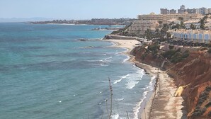 Eine Küstenansicht mit Strand, Meer und Gebäuden im Hintergrund.