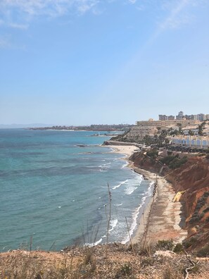 A coastal view with a beach, ocean, and buildings in the background. - Ground Floor in Playa Flamenca With Pool (Orihuela)