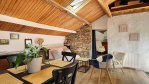 Un coin repas chaleureux avec un plafond en bois, un mur en pierre et une vue sur un intérieur rustique.