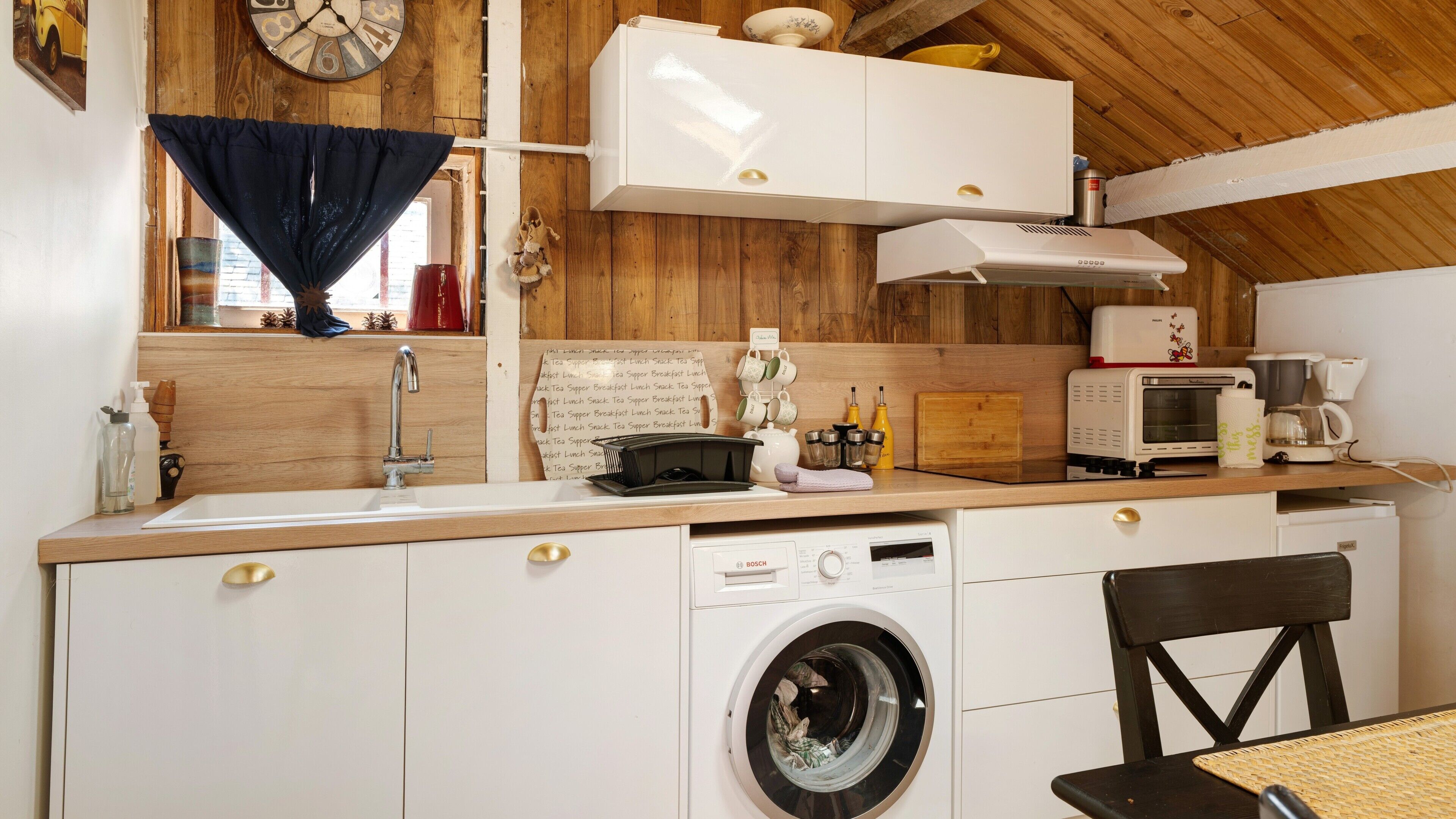 Une cuisine compacte équipée d’un lave-linge, d’un four à micro-ondes et d’une machine à café.