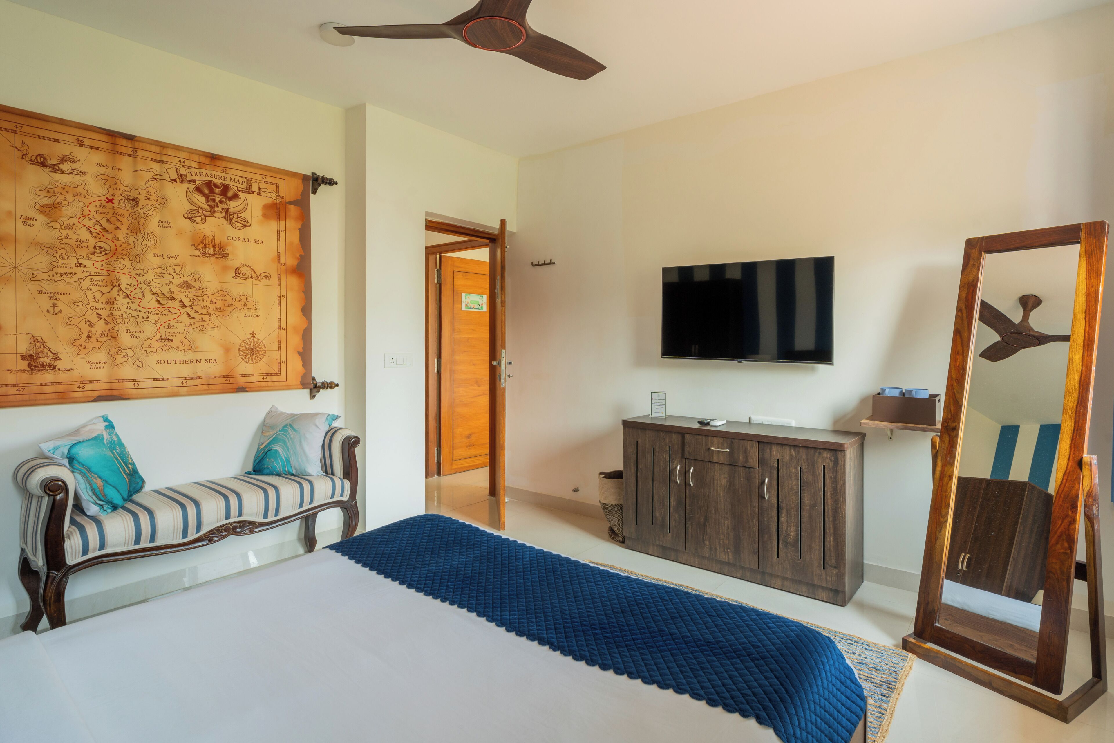 A bedroom with a bed, a wooden headboard, a map, a TV, a wardrobe, and a mirror.