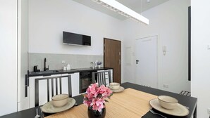 Une cuisine moderne équipée d’un téléviseur à écran plat, d’une porte en bois et d’un coin repas avec une table dressée pour deux personnes.