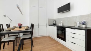 Une cuisine moderne avec des meubles blancs, un plan de travail noir et un four encastré.
