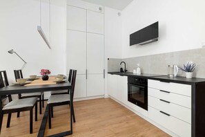 Une cuisine moderne avec des meubles blancs, un plan de travail noir et un four encastré.