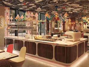 A modern bar area with a counter, seating, and decorative glassware. - Mama Shelter Lake Como  (Como)