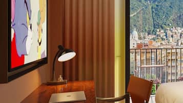 A hotel room with a wooden desk, a laptop, a chessboard, a lamp, a bed, and a view of a cityscape.