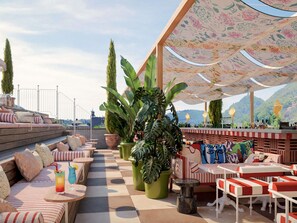 A rooftop bar with outdoor seating, potted plants, and a view of the cityscape. - Mama Shelter Lake Como  (Como)