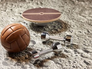 Uma bola de futebol de couro e dois halteres metálicos sobre uma superfície manchada.