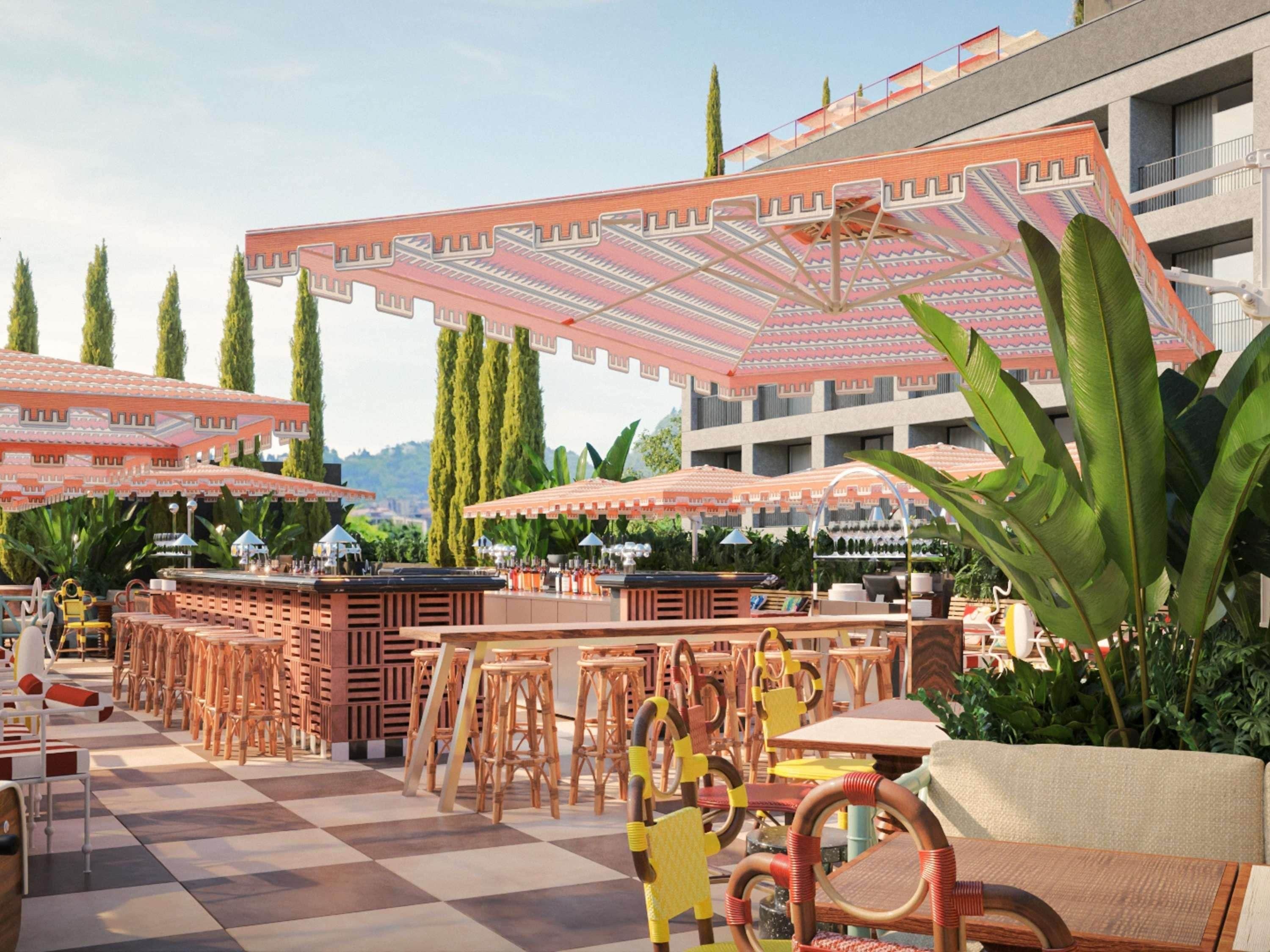 Un espace extérieur aménagé avec des tables, des chaises, des parasols et un bar.