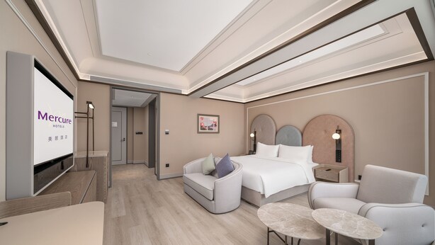A hotel room with a bed, a sofa, a TV, a desk, and a small table. - Mercure Guangzhou Financial City (Guangzhou)
