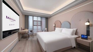 A hotel room with a bed, bedside table, TV, desk, chair, and a large window. - Mercure Guangzhou Financial City (Guangzhou)