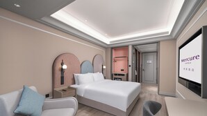 A modern hotel room with a bed, a desk, a chair, a TV, and a bathroom visible through an open door. - Mercure Guangzhou Financial City (Guangzhou)