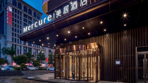 A hotel entrance with a prominent sign, glass doors, and a modern facade.