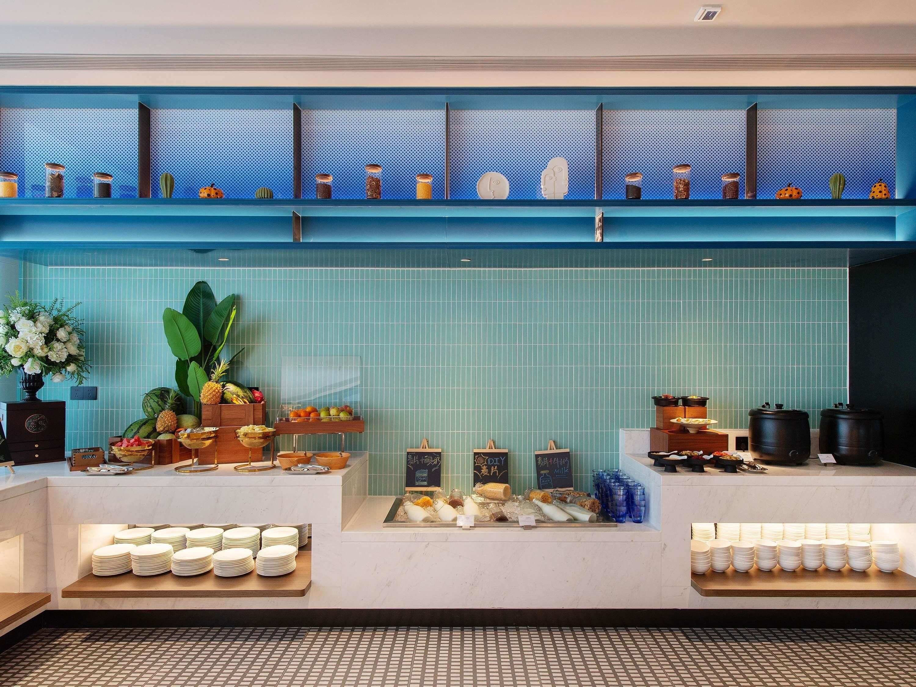 A buffet setup with various food items and a blue decorative shelf above.