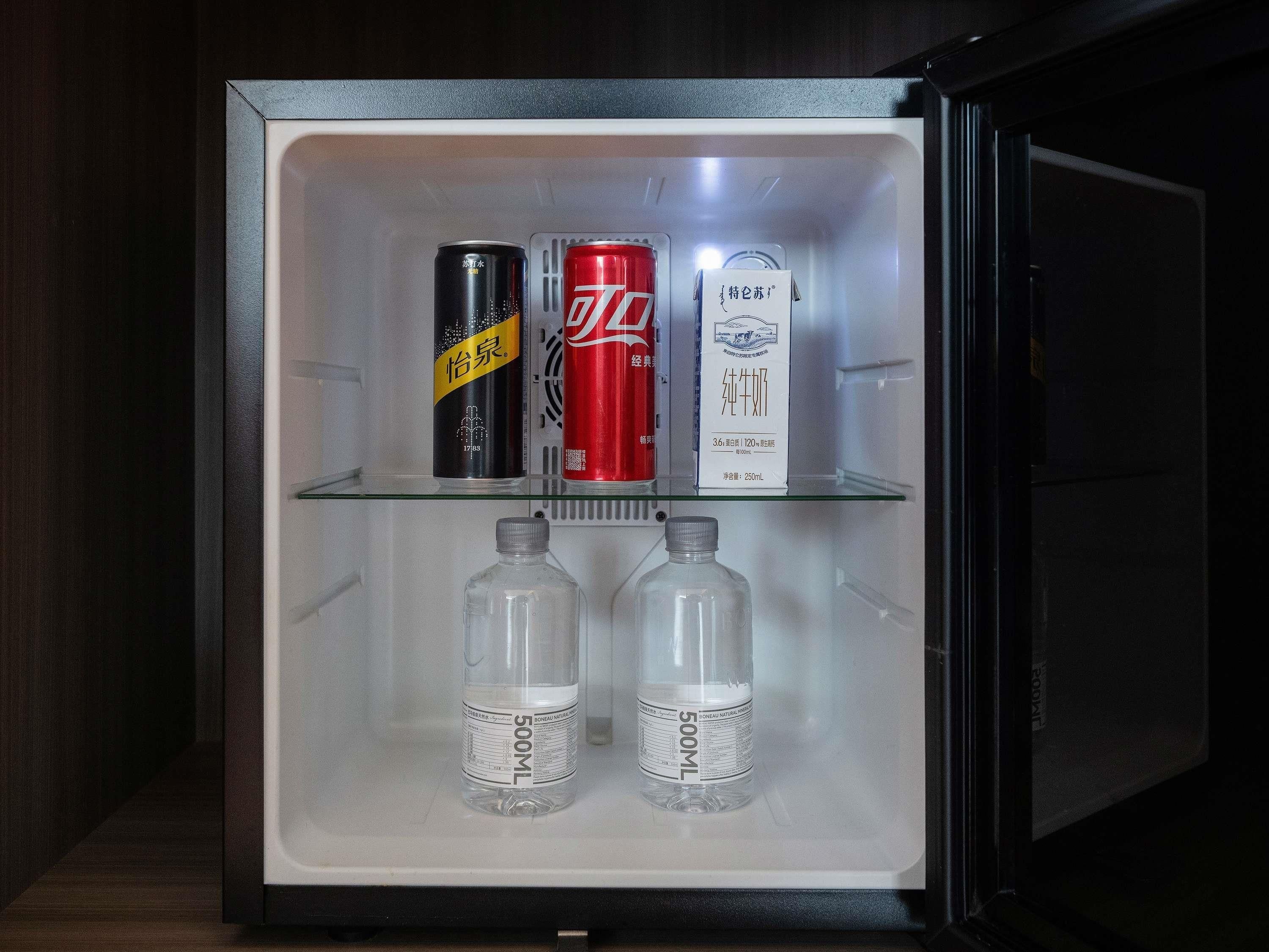 A refrigerator with two 500ml bottles, a black can, and a red can.