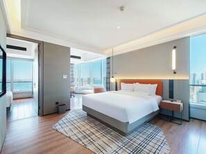 Une chambre dâhĂŽtel moderne avec un grand lit, une vue sur la ville, un bureau et une chaise.