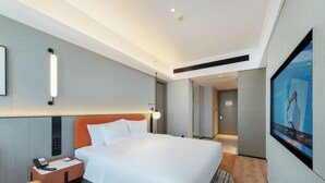 Une chambre d’hôtel avec un lit, un bureau avec un téléphone, une télévision et un miroir.