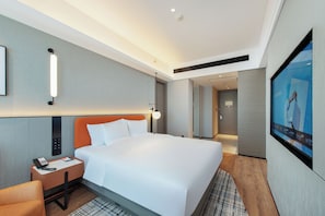 Une chambre d’hôtel avec un lit, un bureau avec un téléphone, une télévision et un miroir.