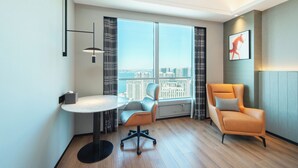 Een moderne kamer met een groot raam, een ronde tafel, twee stoelen en een hangend kunstwerk.