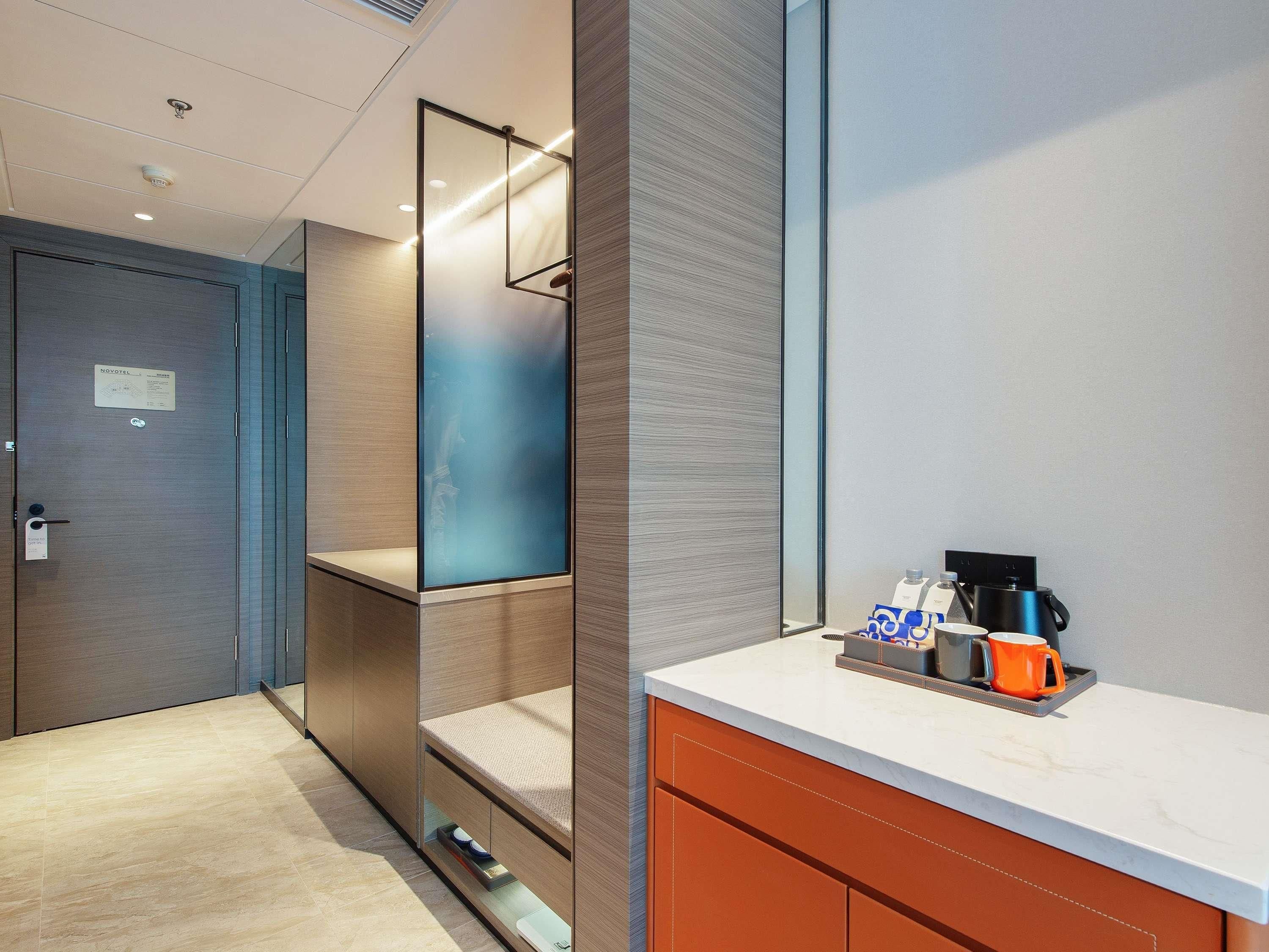 Habitació d'hotel moderna amb bany privat, nevera minibar i zona de cafè.