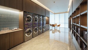 Een moderne wasserette met meerdere wasmachines, een betegelde muur en een schone, gepolijste vloer.