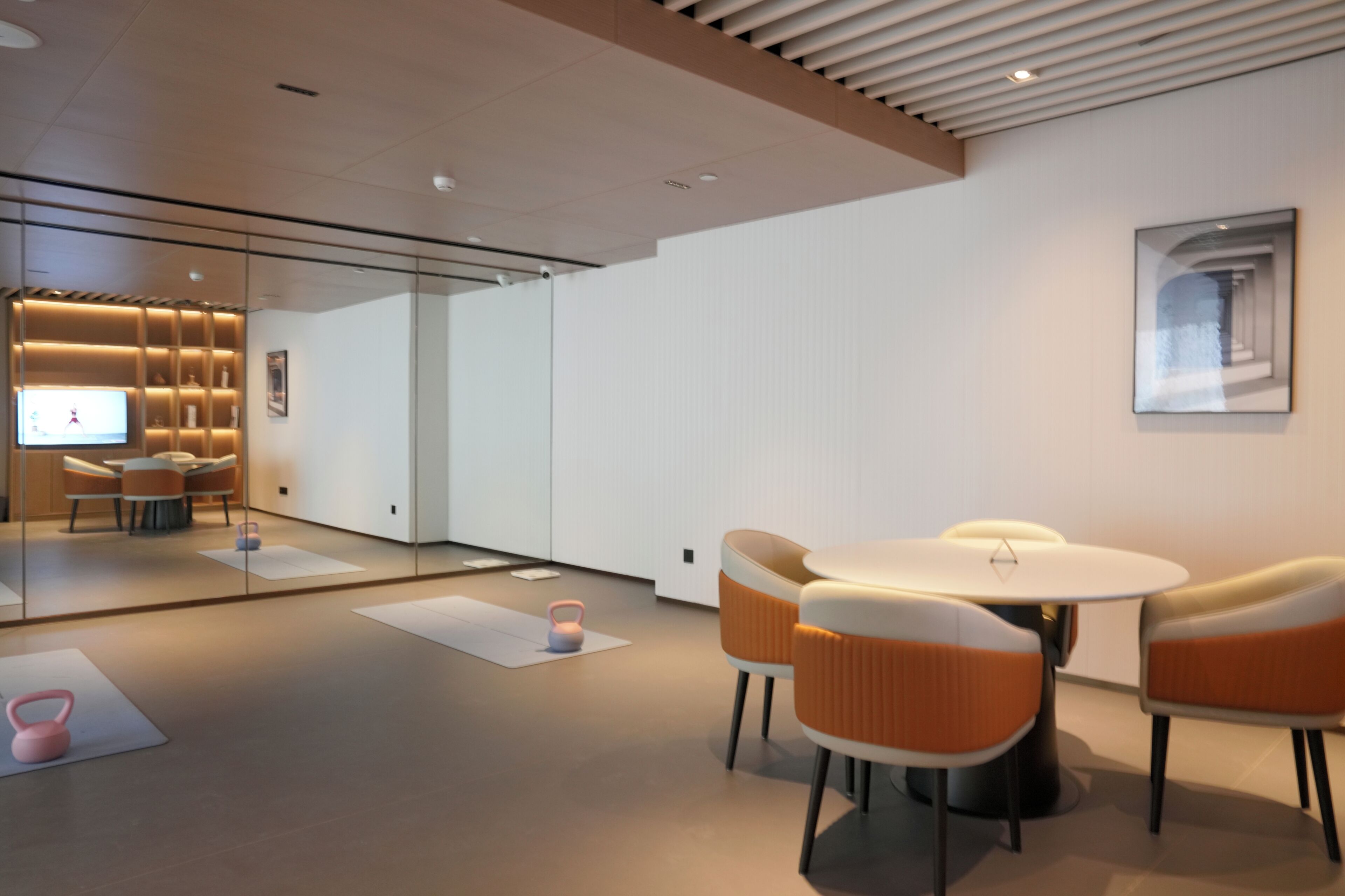 A modern interior with a glass partition, a round table with chairs, and a ceiling with recessed lighting.