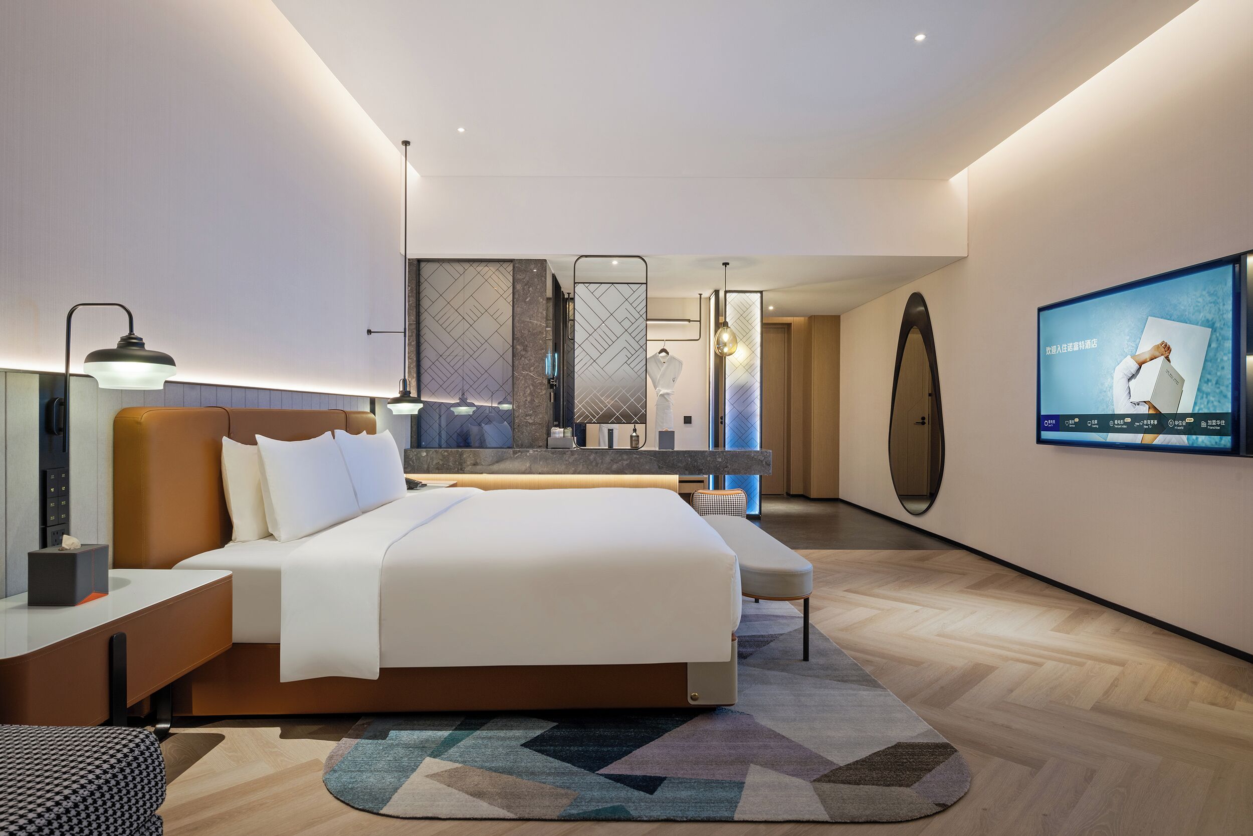 Une chambre d’hôtel moderne avec un grand lit, des tables de chevet, une télévision et un miroir.