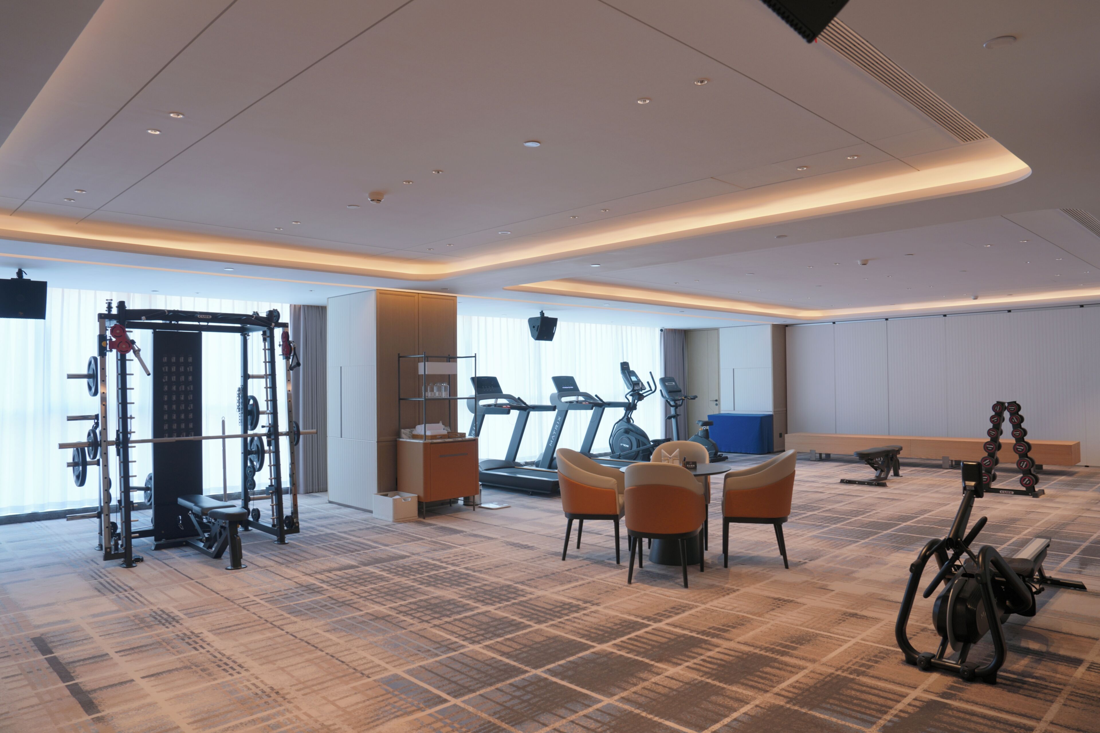 A spacious gym with cardio machines, weightlifting equipment, and a seating area.