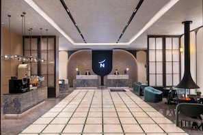 A hotel lobby with a reception desk, seating area, and a large illuminated 'N' sign.