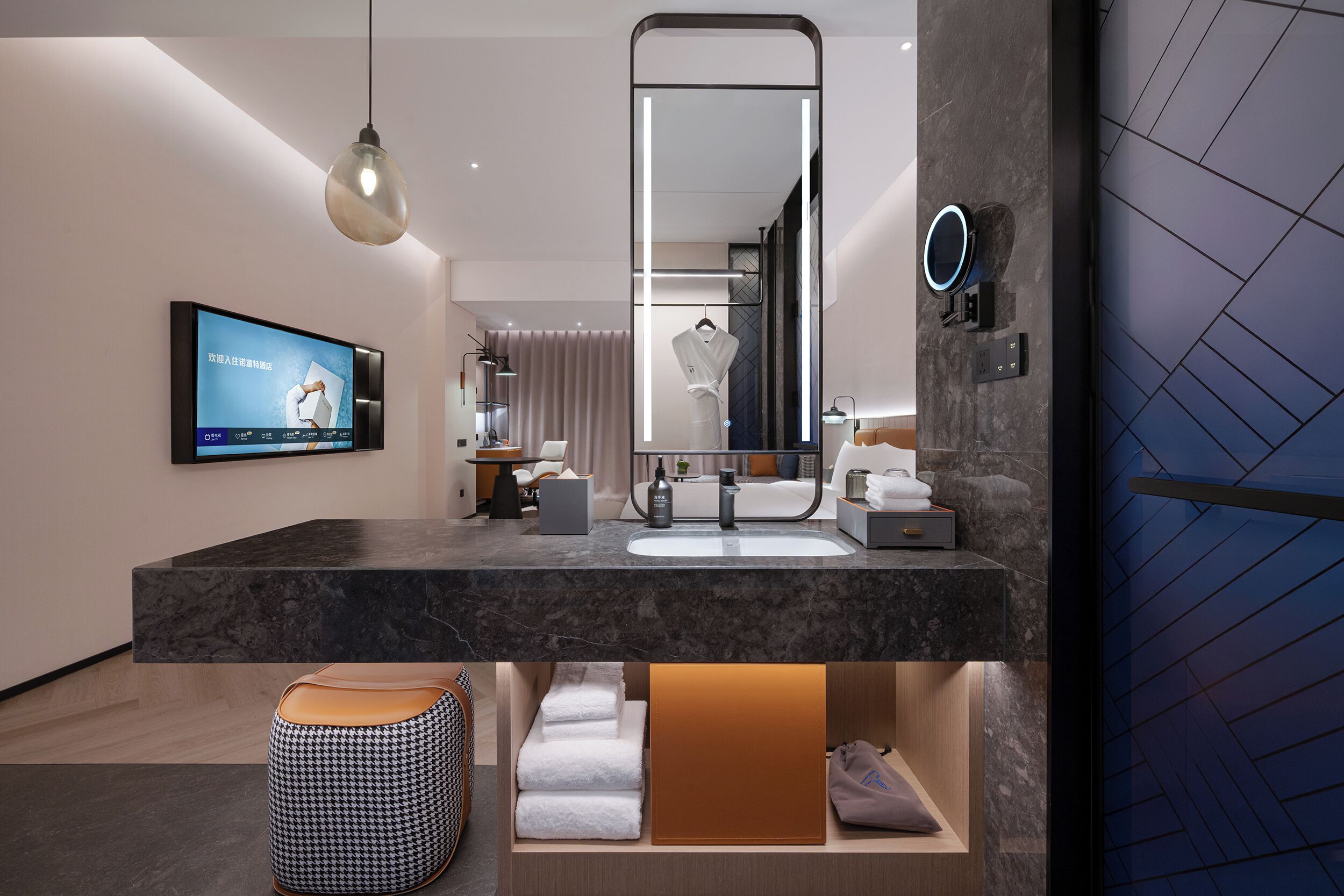 A modern bathroom with a large mirror, a TV, and a towel rack.